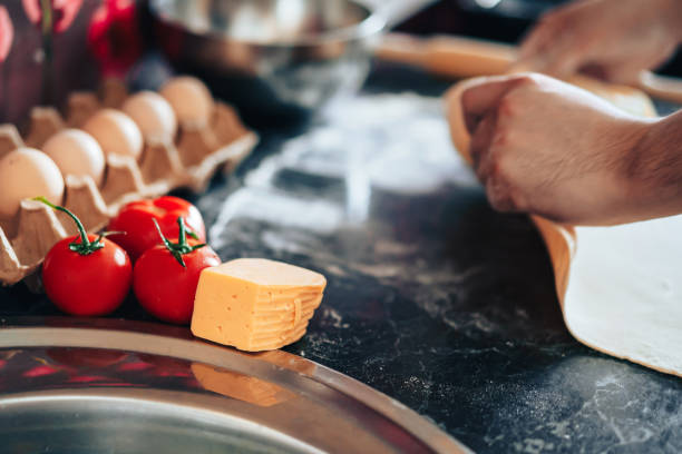 istock Man makes pizza at home in the kitchen. Rolls out the dough with rolling pin 1309776117