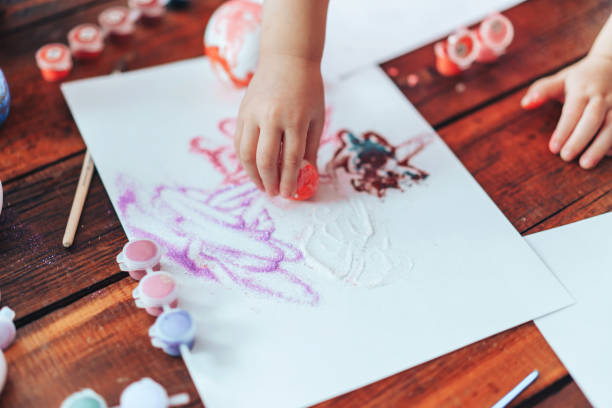 istock Preparing for Easter, child paints eggs on wooden table for religious holiday 1309776145
