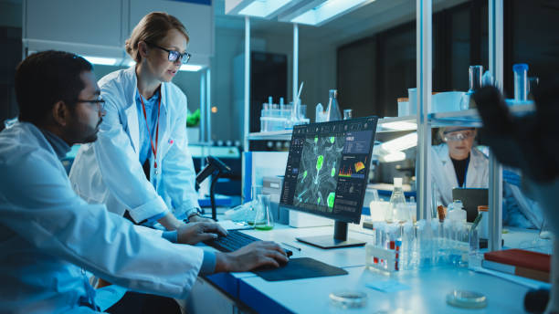 istock Female Research Scientist with Bioengineer Working on a Personal Computer with Screen Showing Virus Analysis Software User Interface. Scientists Developing Vaccine, Drugs and Antibiotics in Laboratory 1309776217