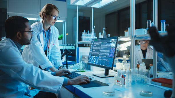 istock Female Research Scientist with Bioengineer Working on a Personal Computer with Screen Showing Gene Analysis Software User Interface. Scientists Developing Vaccine, Drugs and Antibiotics in Laboratory 1309776236