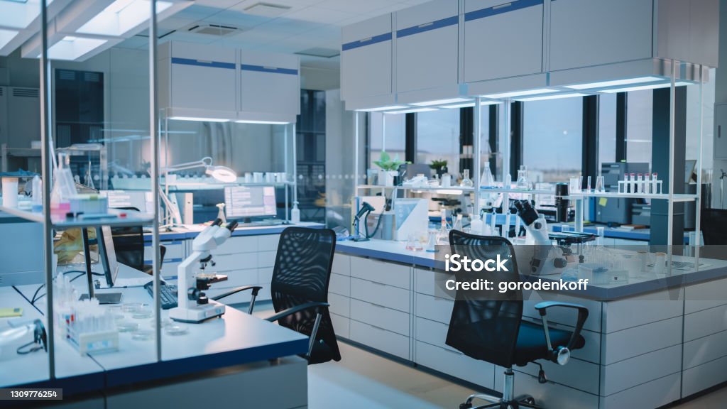 Modern Empty Biological Applied Science Laboratory with Technological Microscopes, Glass Test Tubes, Micropipettes and Desktop Computers and Displays. PC's are Running Sophisticated DNA Calculations. Laboratory Stock Photo