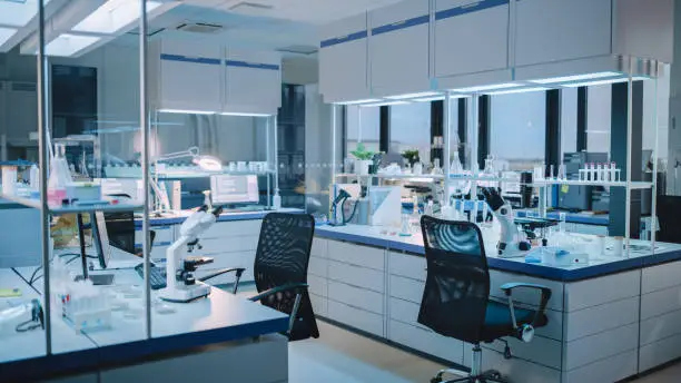 Photo of Modern Empty Biological Applied Science Laboratory with Technological Microscopes, Glass Test Tubes, Micropipettes and Desktop Computers and Displays. PC's are Running Sophisticated DNA Calculations.