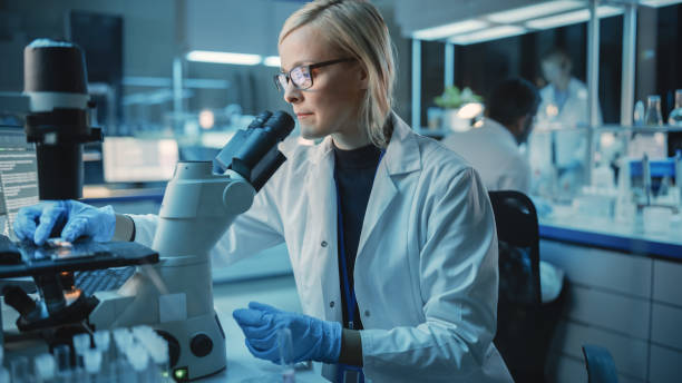 istock Female Research Scientist is Wearing Glasses and Using Modern Microscope to Make Analysis of New Biological Samples. Scientists Workingin Modern Laboratory with Help of High End Technologies. 1309776330