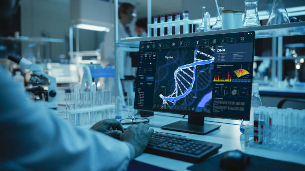 istock Medical Research Scientist Working on Desktop Computer with Gene Analysis Software in Modern Science Research Laboratory. Lab Engineers in White Coats Conduct Experiments in the Background. 1309776374