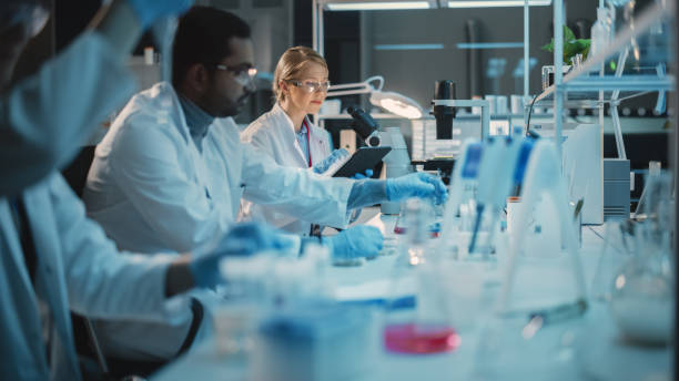 istock Female Research Scientist Uses Digital Tablet Computer to Enter Experiment Data in a Modern Laboratory. Scientists are Conducting Research with the Help of Technology, Microscope and Micropipettes. 1309776391