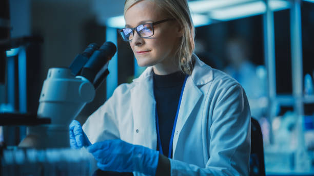 istock Portrait of a Medical Research Scientist Conducting DNA Experiments Under a Microscope in a Biological Applied Science Laboratory. Beautiful Female Lab Engineer in White Coat. 1309776461