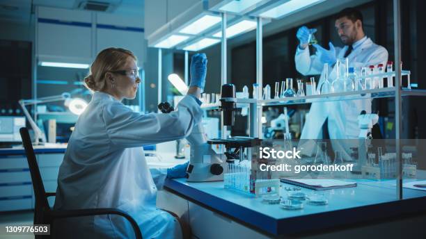 Female Medical Research Scientist Looks At Biological Samples Before Analysing It Under Digital Microscope In Applied Science Laboratory Lab Engineer In White Coat Working On Vaccine And Medicine Stock Photo - Download Image Now