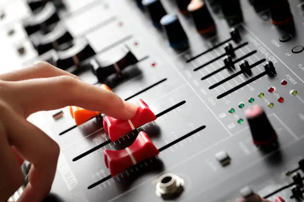 Female hand adjusting the volume in the sound mixer board.