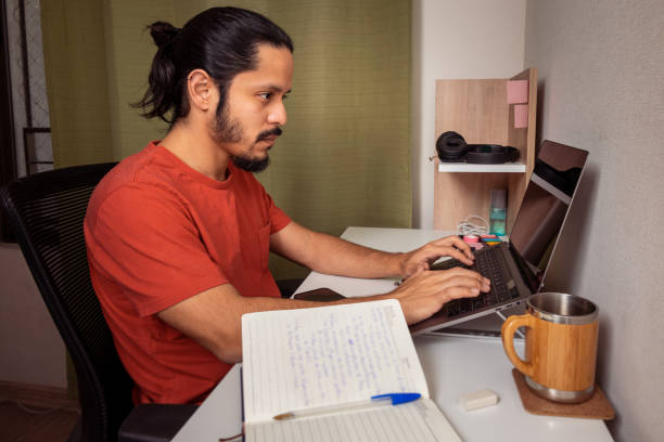 istock Young man doing homework and studying at home. Man working at home. 1309778372