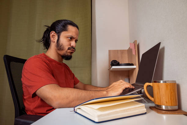 istock Young latin man doing homework and studying at home. Man working at home. 1309778406