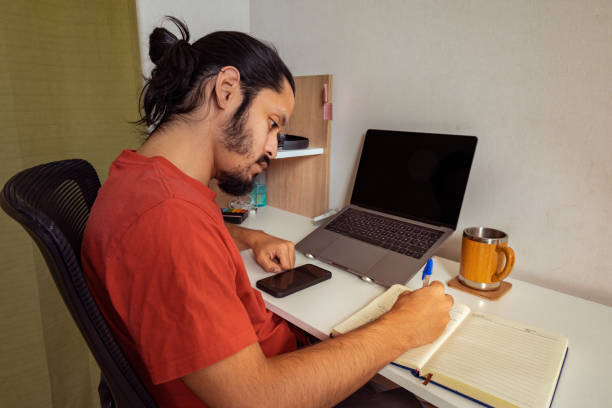 istock Young man doing homework and studying at home. Man working at home. 1309778420