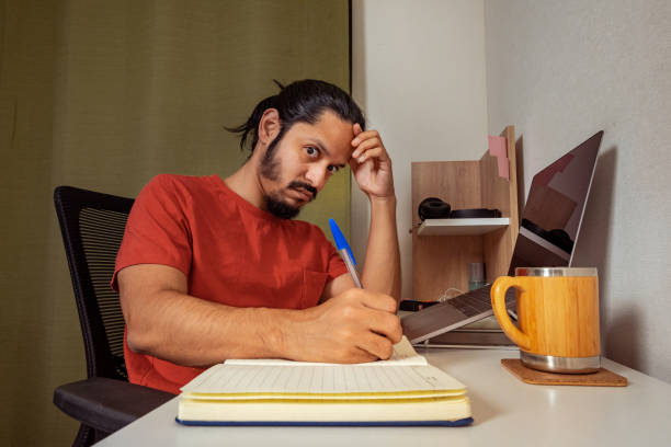 istock Young man doing homework and studying at home. Man working at home. 1309778426