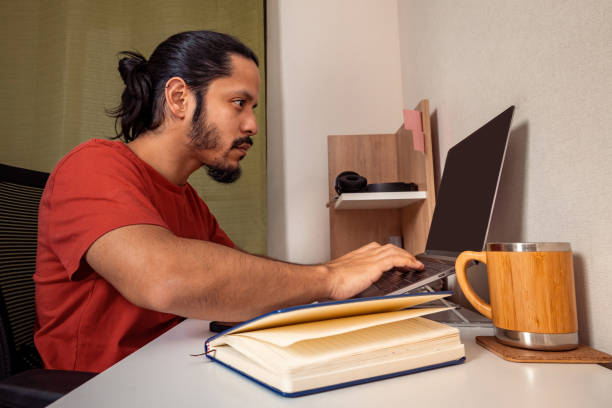 istock Young latin man doing homework and studying at home. Man working at home. 1309778453