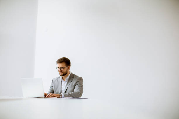 istock Young man working on laptop in bright office 1309779894