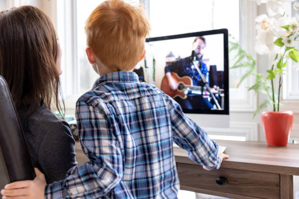 a mother and her son are watching an online music concert from home for her birthday during covid-19 pandemic - band 40s imagens e fotografias de stock