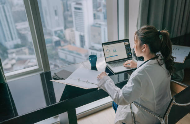 asian chinese female doctor working on medical report with laptop and document file asian chinese female doctor working on medical report with laptop and document file job centre stock pictures, royalty-free photos & images