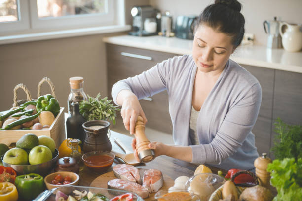 istock woman cooking in the kitchen ( with fish salmon) 1309783462