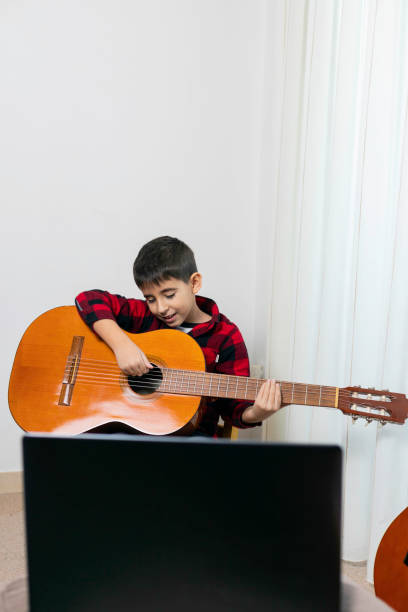istock The child practices playing the classical Spanish guitar with the computer from home 1309784207
