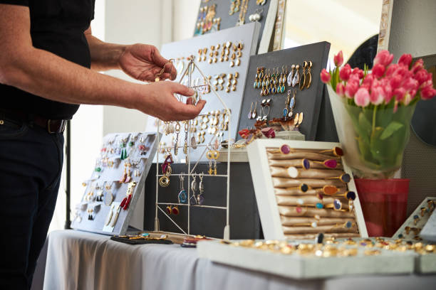 Handcrafter hanging a gold earring on the metal display rack Cropped photo of a professional male jeweler organizing his new stylish jewels on the jewelry stand jewelry craftsperson craft jeweller stock pictures, royalty-free photos & images