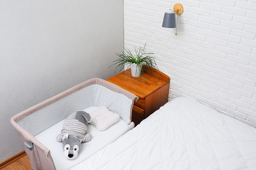 a side bed for a newborn on the background of a white brick wall.