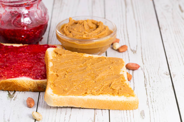 istock Toasts with peanut butter and berry jam on light wooden background 1309787537