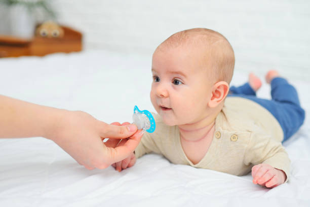 istock hand gives a pacifier to her baby son on a white background 1309787550