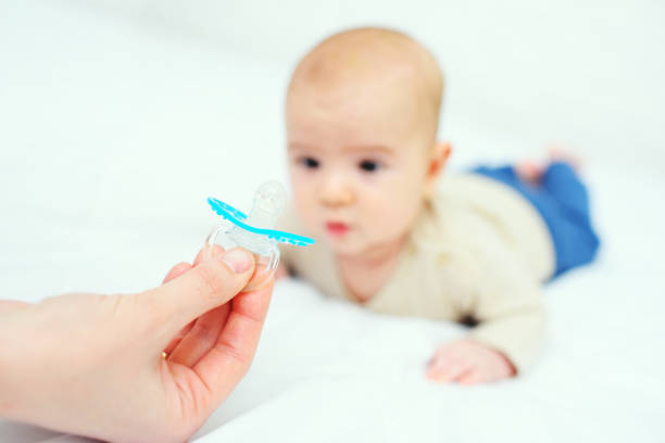 istock hand gives a pacifier to her baby son on a white background 1309787587