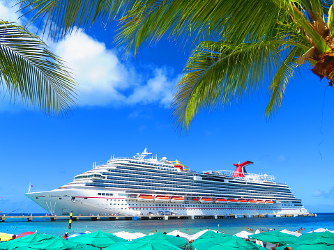 Summer of 2017- The beautiful Carnival Vista sits at the dock of Grand Turk in the Caribbean. It is a sunny day and the ship is stunning, with palm trees swaying in front of her. The view is from the beach at Margaritaville.
