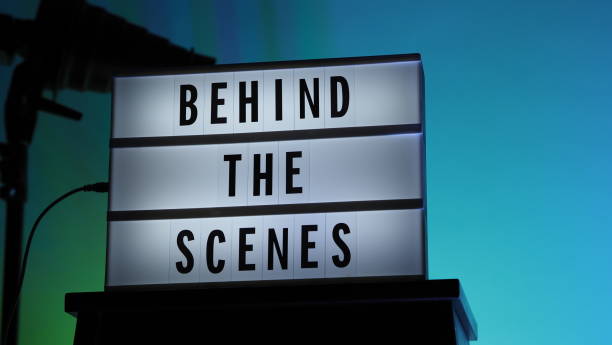 Behind the scenes letterboard text on Lightbox or Cinema Light box. Multi color LED on background. Sillhouette flash snoot hood on tripod. video production studio. Behind the scene Lightbox