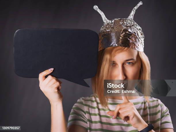 Girl In A Foil Hat Making A Sign Of Silence With A Blank Black Board Stock Photo - Download Image Now