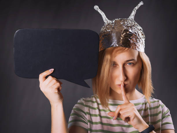 girl in a foil hat making a sign of silence with a blank black board - tin foil hat imagens e fotografias de stock