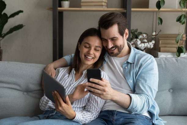 istock Close up young couple having fun with mobile devices together 1309791017