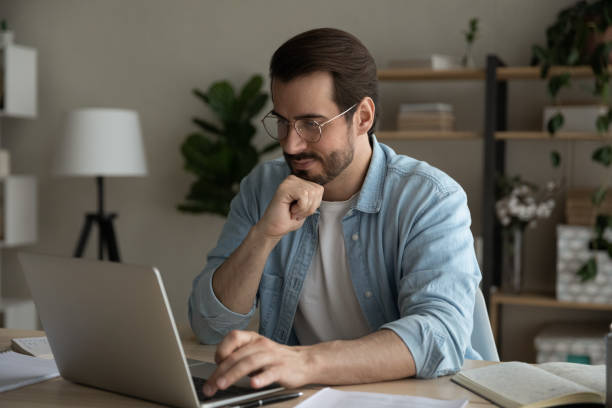 istock Close up thoughtful man wearing glasses looking at laptop screen 1309791067