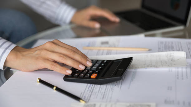 istock Close up woman planning budget, counting bills, using calculator 1309798033