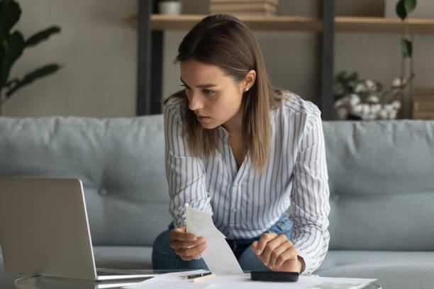 istock Close up serious woman calculating expenses, using laptop, checking documents 1309798036
