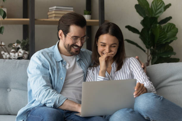 istock Close up happy laughing young couple watching video, using laptop 1309798583