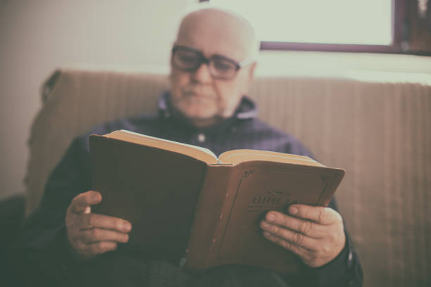 Midsection Of Man Reading Book Outdoors