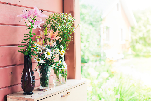 Home decor. Wildflowers in a vase on a background of wooden pink boards. Summer