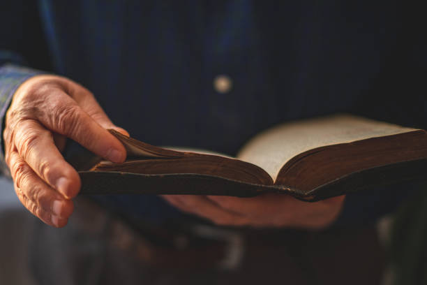 Old Bible in hands of an old man stock photo