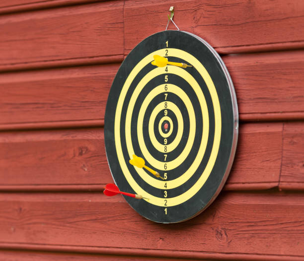 istock Dart board on a red wall. Two yellow and one red arrow... 1309803709