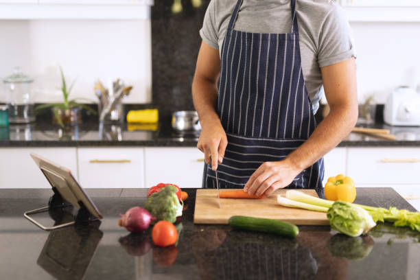 istock Caucasian man in kitchen wearing apron and cutting vegetables 1309804926