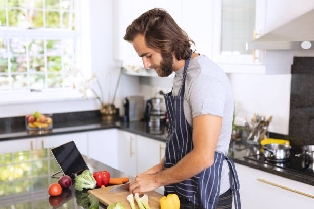 istock Caucasian man in kitchen wearing apron and cutting vegetables 1309804960