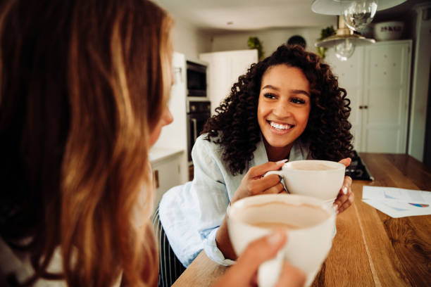istock Mixed race friends laughing together in kitchen drinking hot coffee 1309805251