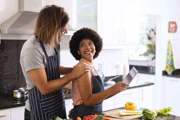 istock Happy diverse couple in kitchen embracing and using tablet 1309805260