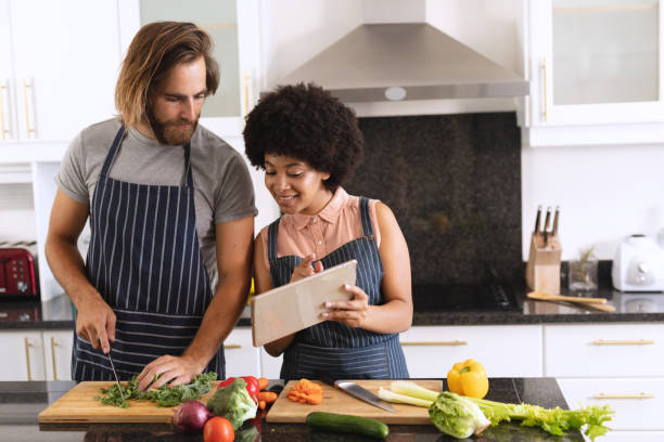 istock Happy diverse couple in kitchen using tablet and preparing food 1309805303