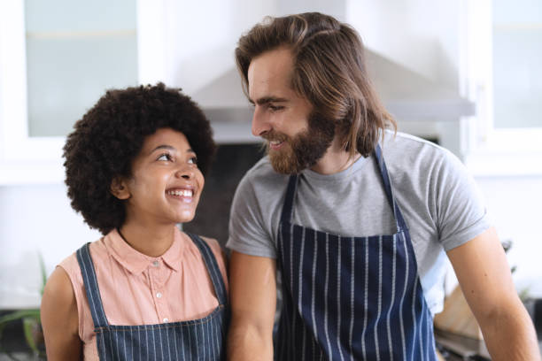 istock Happy diverse couple in kitchen embracing and smiling 1309806760