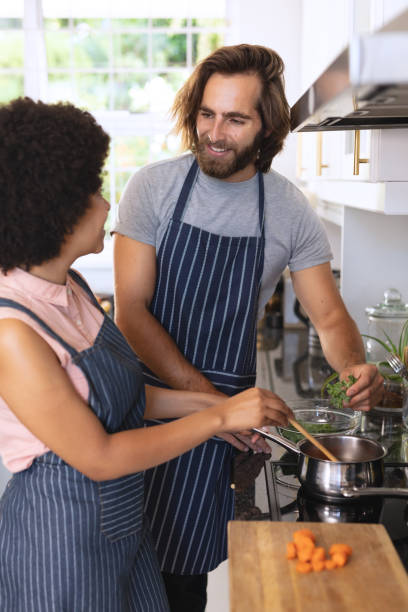 istock Happy diverse couple in kitchen preparing food and smiling 1309807645
