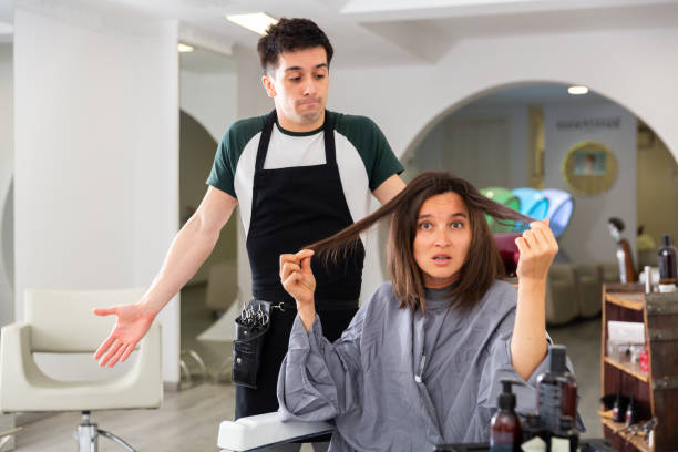 Woman displeased with new haircut in hairsalon Portrait of shocked woman displeased with new haircut and regretting hairdresser in modern hairsalon angry hairstylist stock pictures, royalty-free photos & images