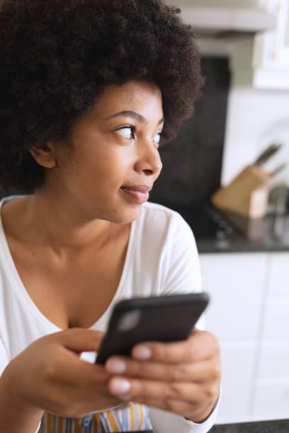 istock African american woman sitting in kitchen using smartphone and thinking 1309809227