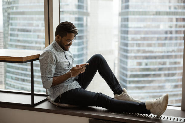 istock Side view smiling African American man using phone near window 1309809634